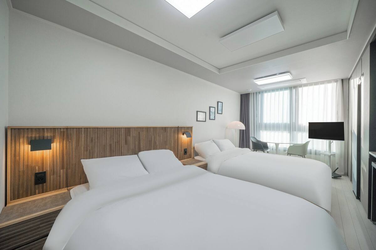 A hotel room with two beds, a wooden headboard, a flat-screen TV, and a balcony with a view.