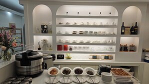 A kitchen area with a buffet setup, including various dishes and utensils on the counter, and shelves with kitchenware and bottles in the background. - Daegu Dongseongro Star B&B Business Hotel (Daegu)