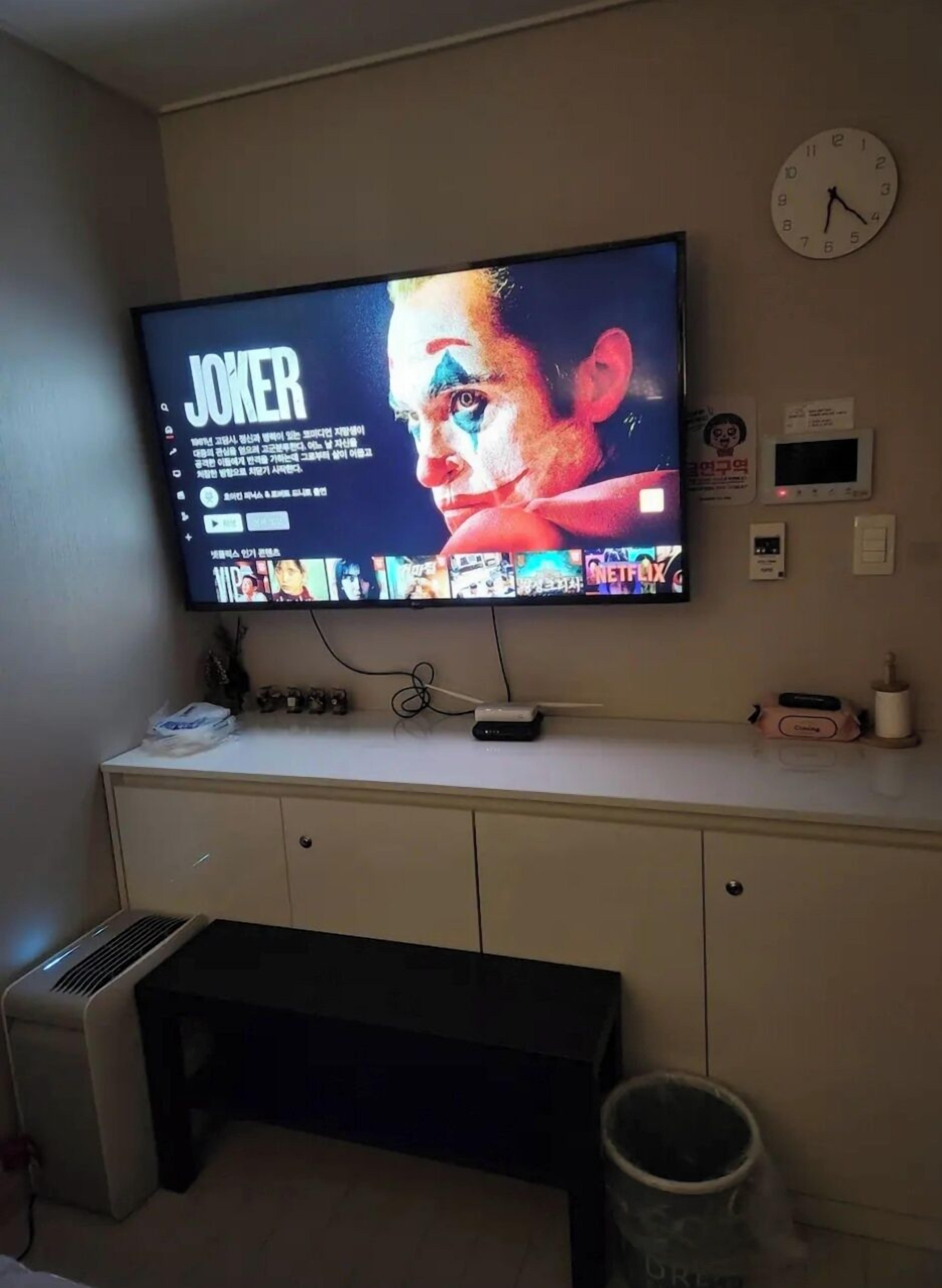 A television mounted on a wall displaying a movie titled "JOKER".