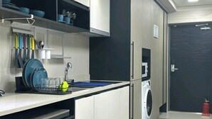 A modern kitchen with white cabinets, a built-in washing machine, and a black door. - Daegu Dongseongro Star B&B Business Hotel (Daegu)