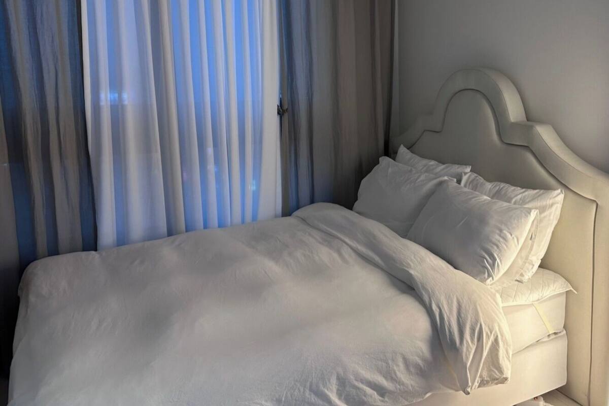 A neatly made bed with white bedding in a room with a simple, modern design.