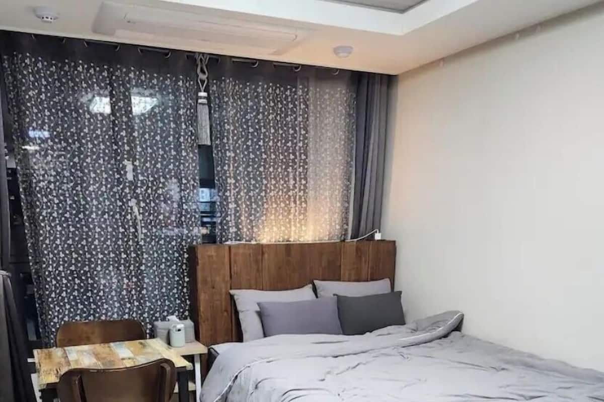 A bedroom with a bed, a desk, and a chair.
