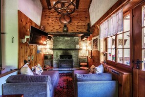 A cozy room with a stone fireplace, wooden walls, and a television mounted on the wall.