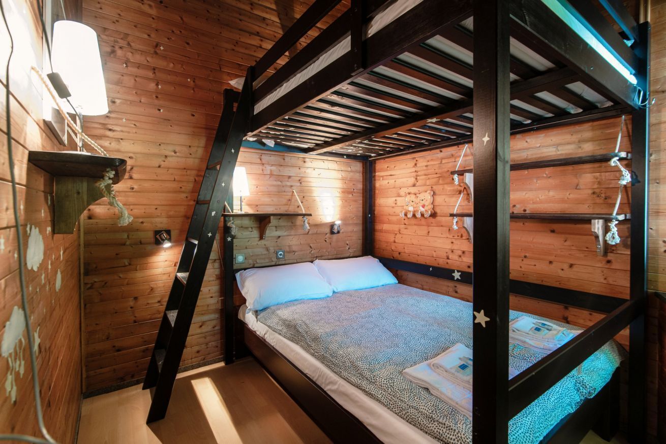 A bunk bed room with wooden walls and a slanted ceiling.