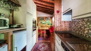 Una cocina estrecha con armarios de madera, una mesa de comedor roja y una alfombra estampada.