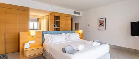 A hotel room with a bed, bedside table, lamp, and a wall-mounted TV.