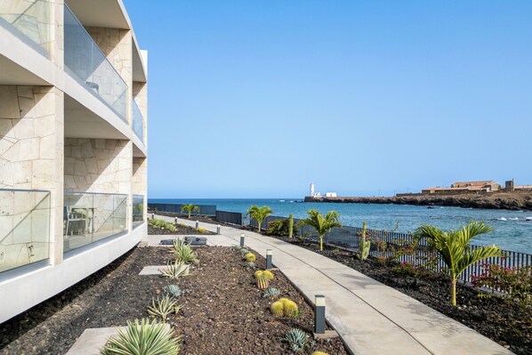 Un edificio costero con vista despejada al mar y un faro a lo lejos.