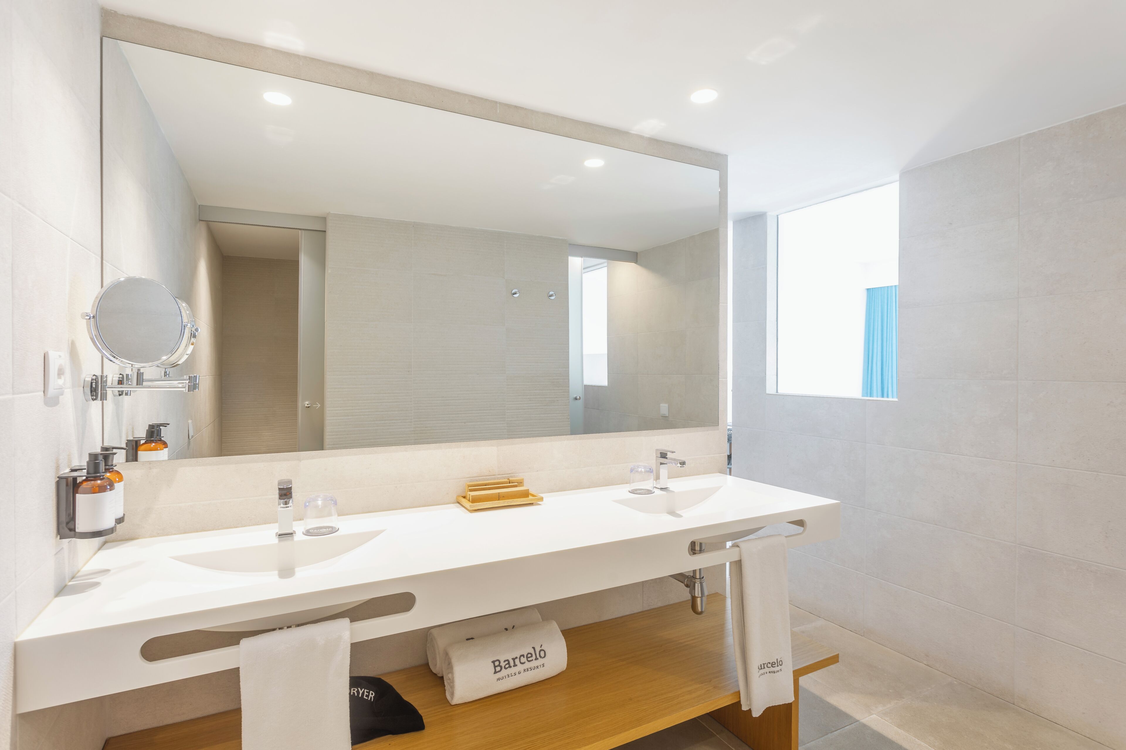 Un baño moderno con dos lavamanos, un espejo grande y una ventana.