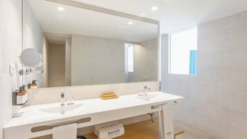 Un baño moderno con dos lavamanos, un espejo grande y una ventana.