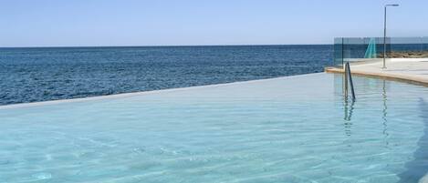 A clear blue pool with a view of the ocean.