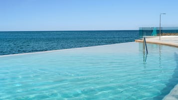 Alberca al aire libre, sombrillas en la alberca y camastros