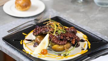 Un plato con pulpo, limón y adornos sobre un plato negro.