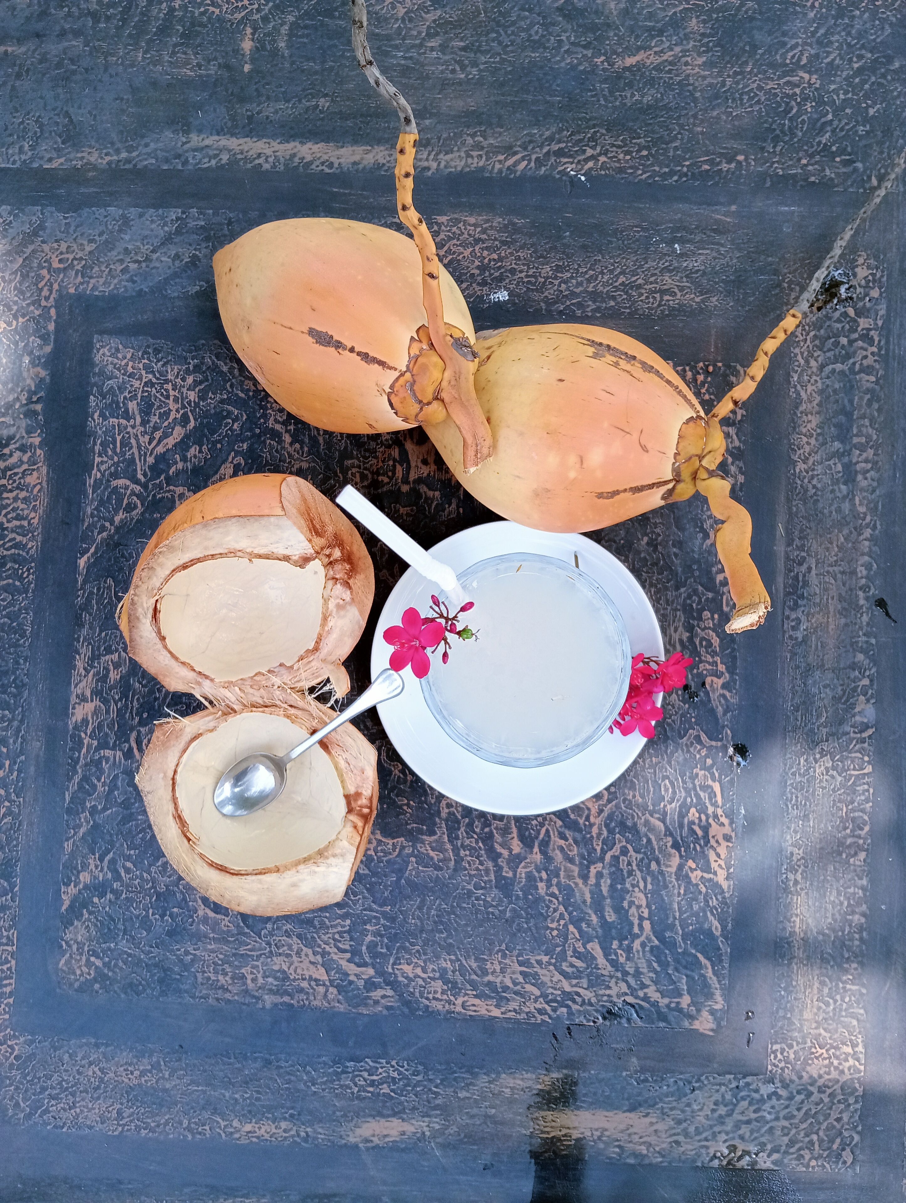 A coconut and a glass of water on a textured surface.
