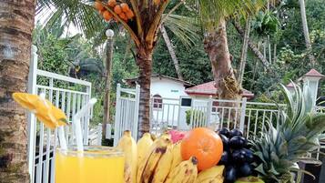 A table with a fruit basket, a glass of orange juice, and a whole pineapple.