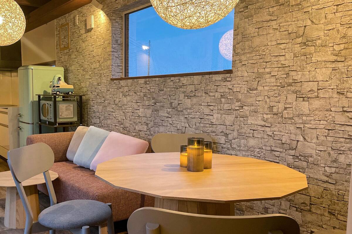 A cozy dining area with a stone wall, a large window, and a table with candles.