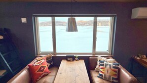 Ein gemütlicher Raum mit großem Fenster, einem Holztisch und einer gepolsterten Bank.