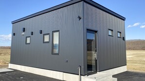Ein modernes, eingeschossiges Gebäude mit grauer Fassade, großen Fenstern und einer flachen Dachfläche.