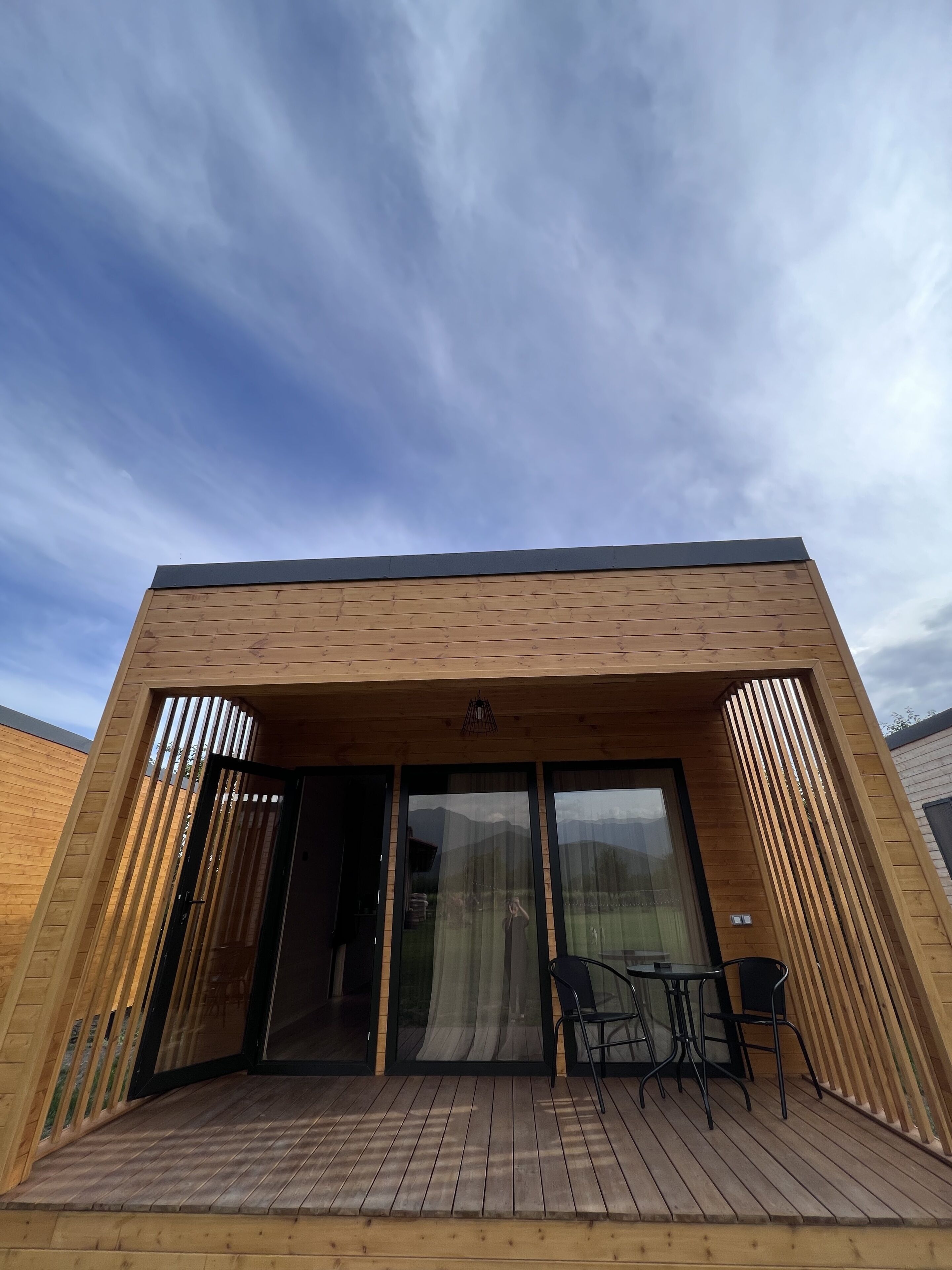 A modern wooden building with a deck and sliding glass doors.