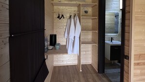 Un intérieur en bois comprenant un coin cuisine, un luminaire suspendu et une porte donnant accès à une salle de bain.
