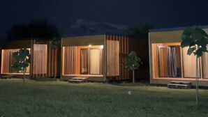 Une rangée de chalets modernes de plain-pied, dotés de grandes fenêtres, chacun ayant un petit porche et un arbre devant.