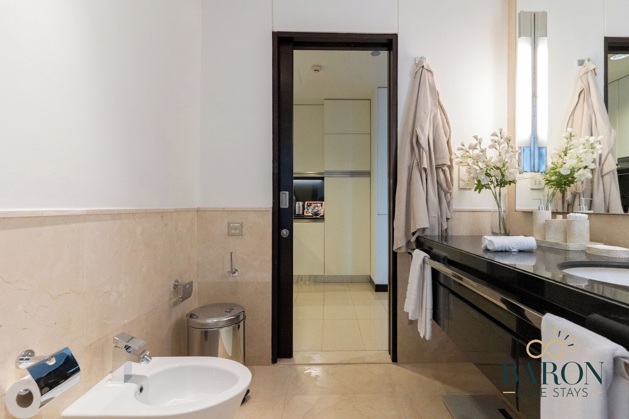 A modern bathroom with a sink, mirror, and towels.