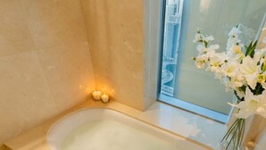 A modern bathroom with a freestanding bathtub, a glass shower enclosure, and a vase of white flowers on the windowsill. - Luxe High Floor In Address Marina.36 (Dubai)