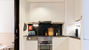 A compact kitchen with a stove, oven, and a coffee maker. - Luxe High Floor In Address Marina.36 (Dubai)