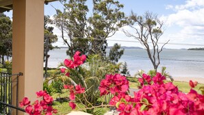 A view of a lake with trees and flowers in the foreground.