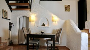 Un espace repas comprenant une table et des chaises, un escalier et des luminaires fixés au mur.