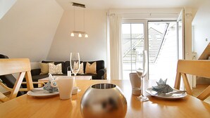 A dining area with a wooden table, a glass vase, and a sofa with cushions.