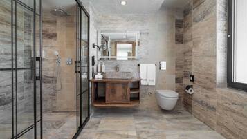 A modern bathroom with a glass shower enclosure, a wooden vanity, and a marble-tiled floor.
