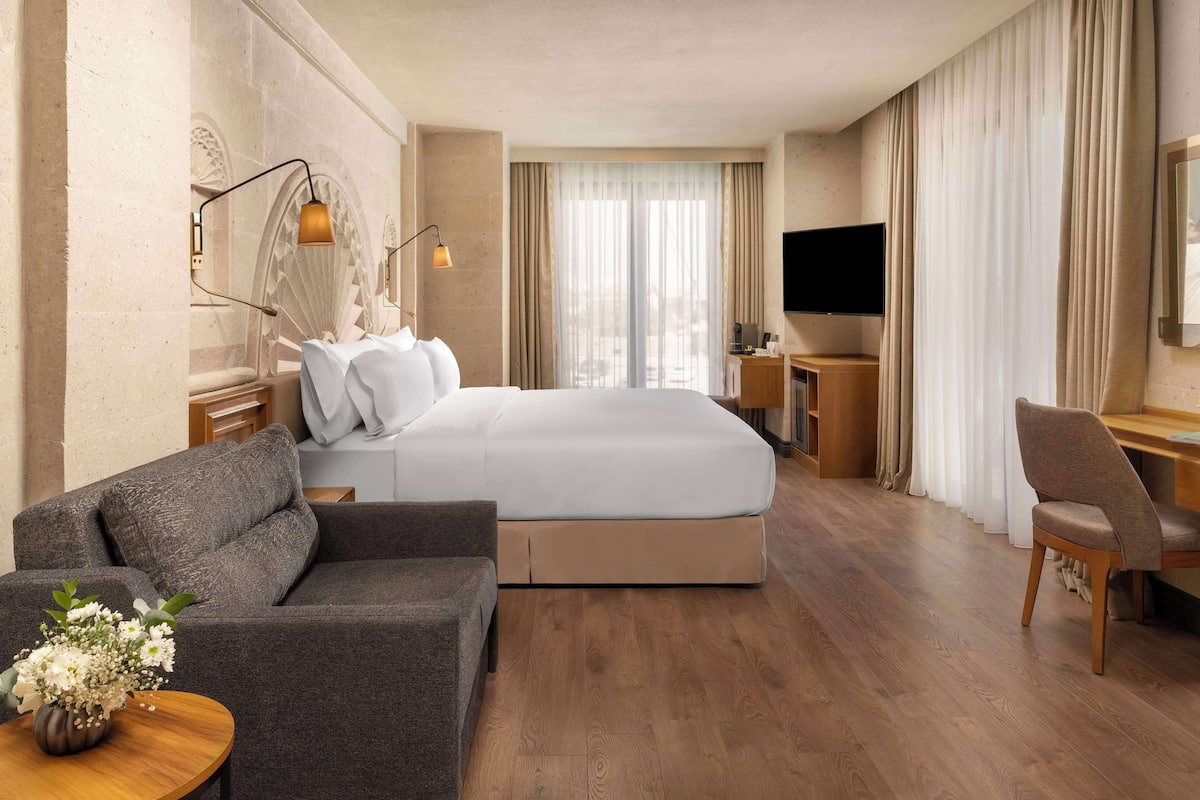 Ein Hotelzimmer mit einem großen Bett, einer Couch, einem Schreibtisch und einem Fernseher.