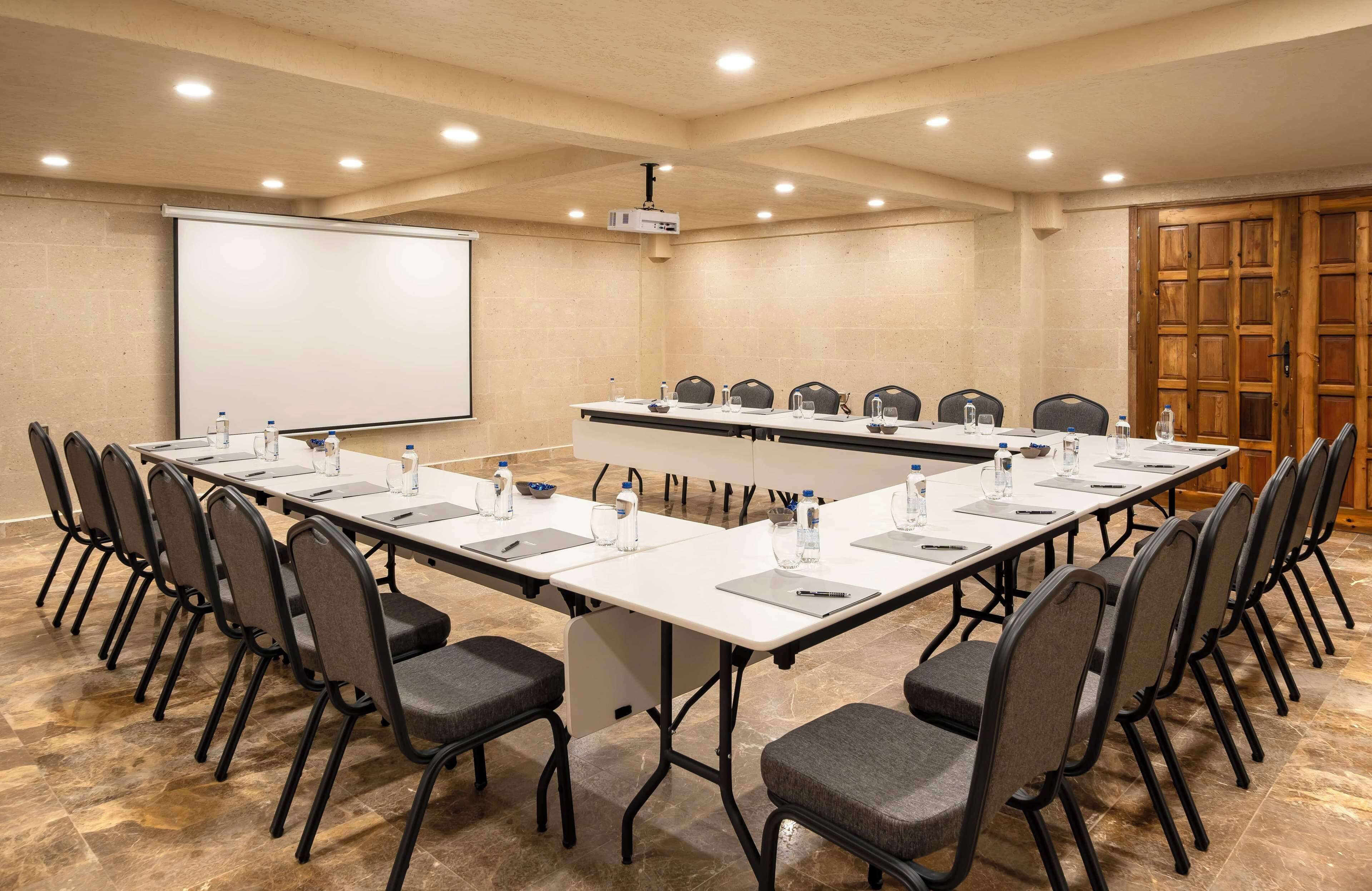 A conference room with a long table, chairs, a projector screen, and a whiteboard.