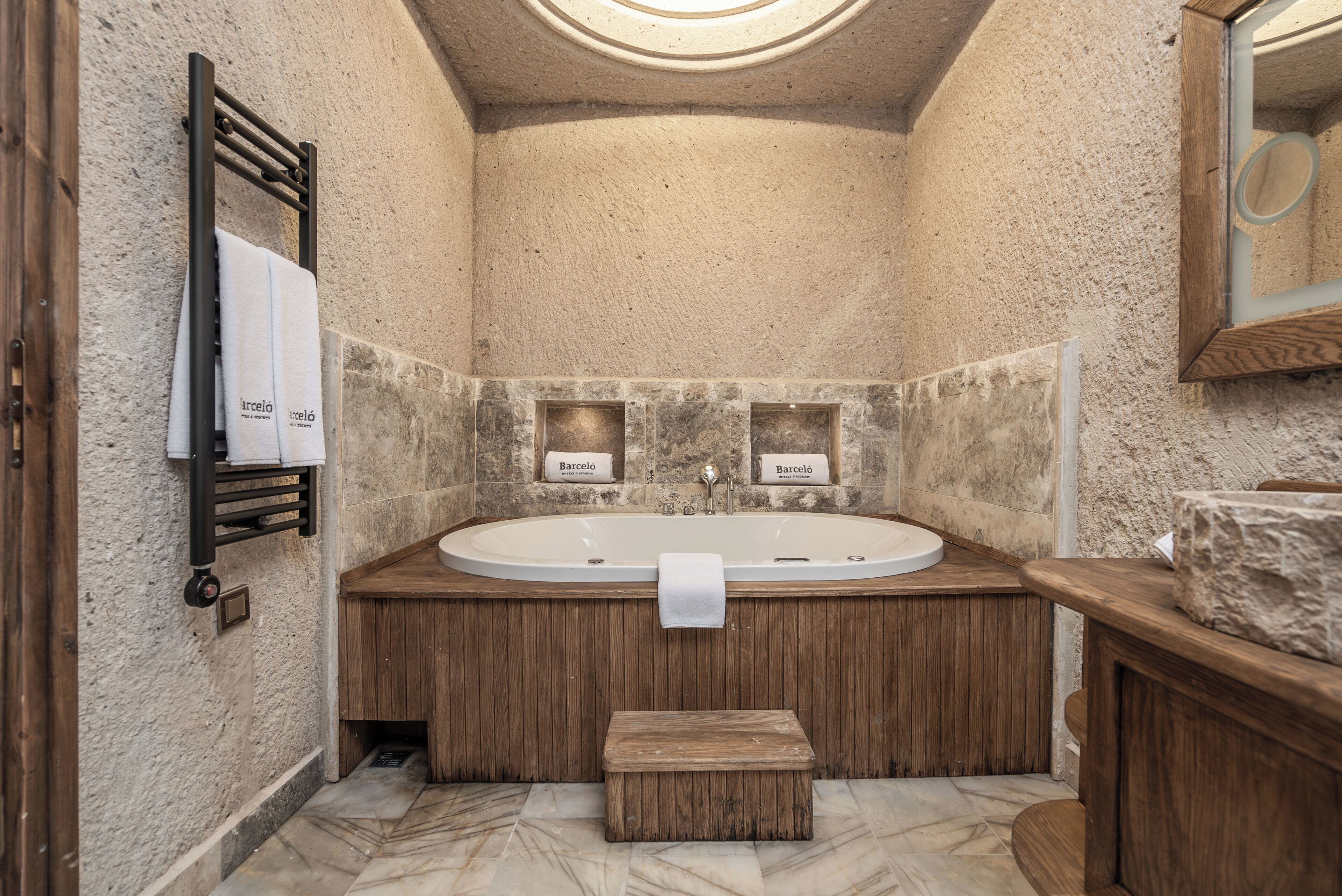 A bathroom with a freestanding bathtub, wooden vanity, and a small bench.