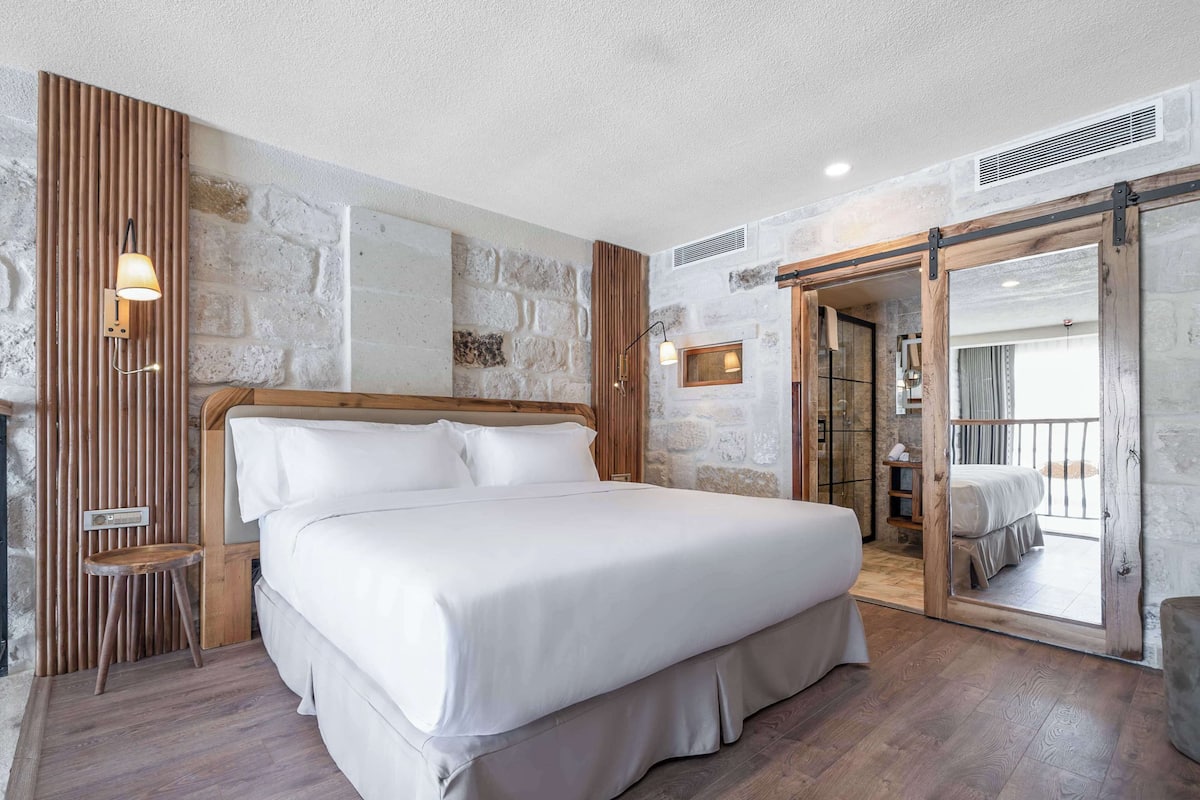 Ein Schlafzimmer mit einem großen Bett, einem Holz-Kopfteil und Blick auf einen Balkon.
