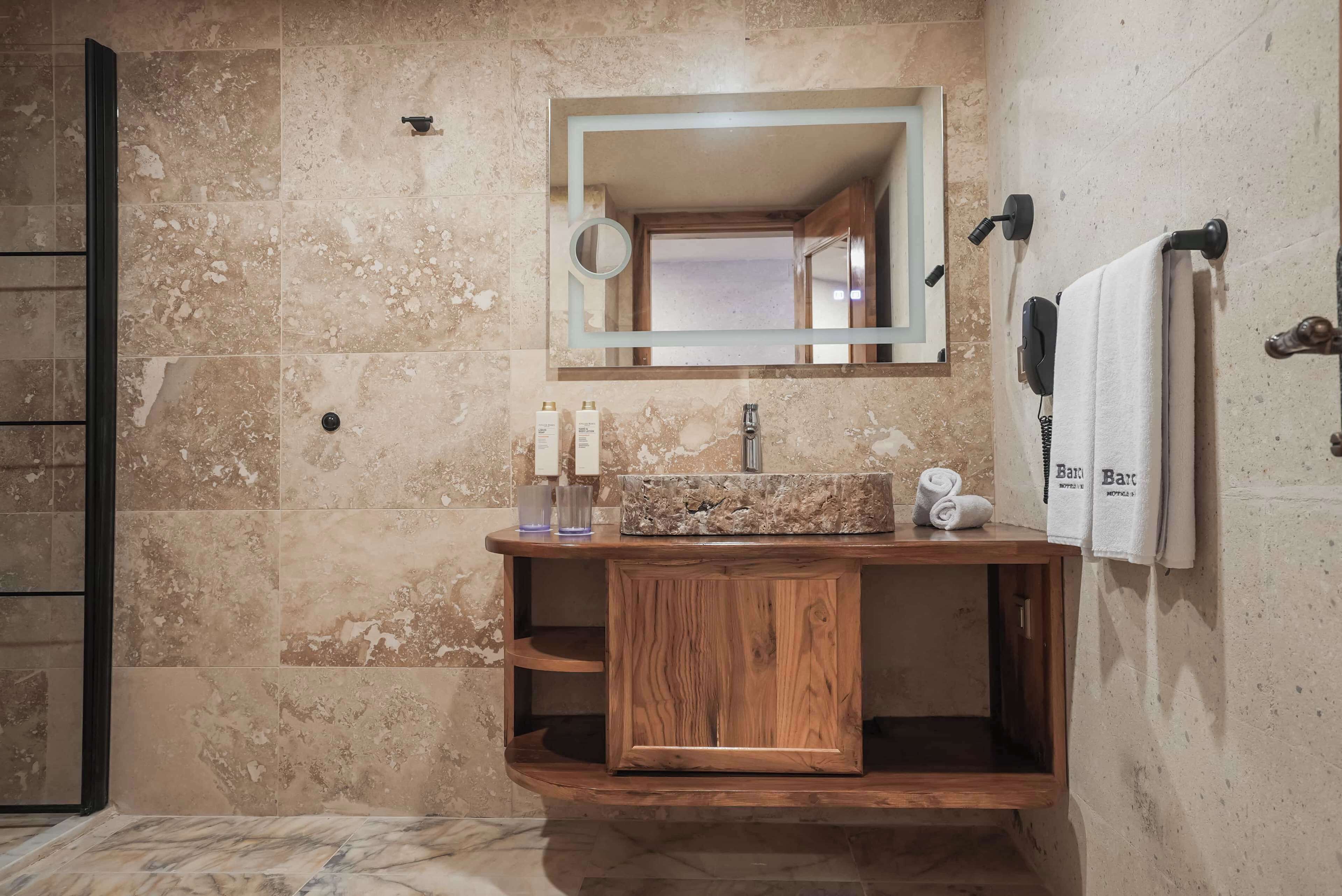 Un baño con tocador de madera, un espejo y un perchero para toallas.