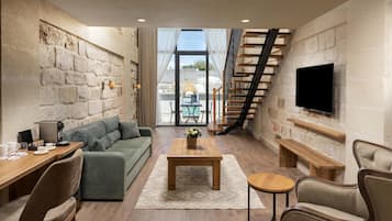 A modern living room with a stone wall, a sofa, a coffee table, and a TV mounted on the wall.
