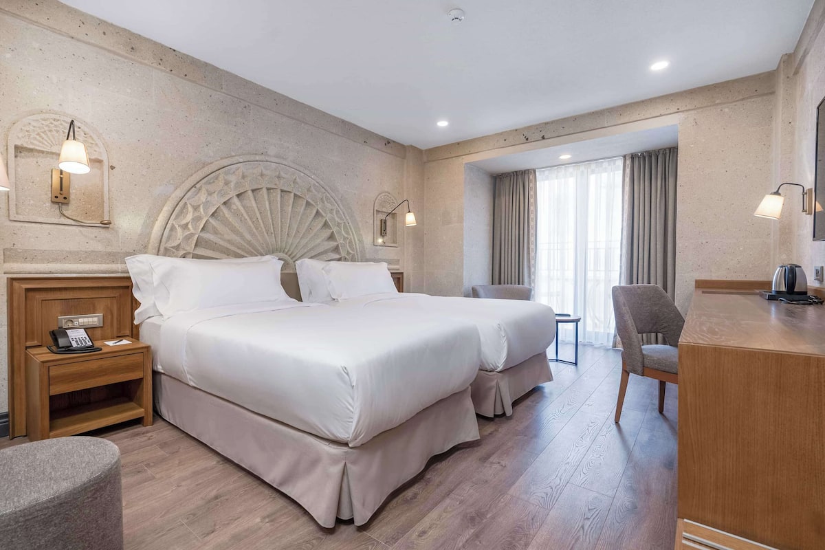Ein Hotelzimmer mit einem großen Bett, Nachttischen, einem Schreibtisch und einem Stuhl.
