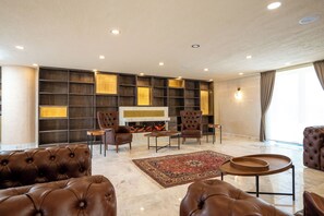 A spacious living room with a fireplace, leather sofas, a coffee table, and a large wall-mounted TV.