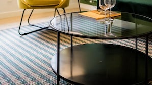 A modern living room with a round glass coffee table, a yellow armchair, a dark green sofa, and a floor lamp. - SUNRISE BEACH APARTMENT by Sweet Home (San Sebastián)