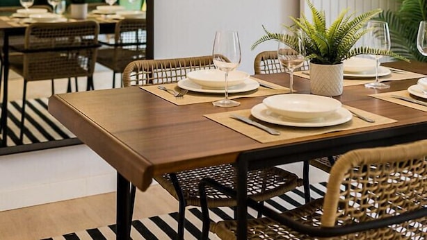 A dining area with a wooden table set for four, surrounded by wicker chairs. - SUNRISE BEACH APARTMENT by Sweet Home (San Sebastián)