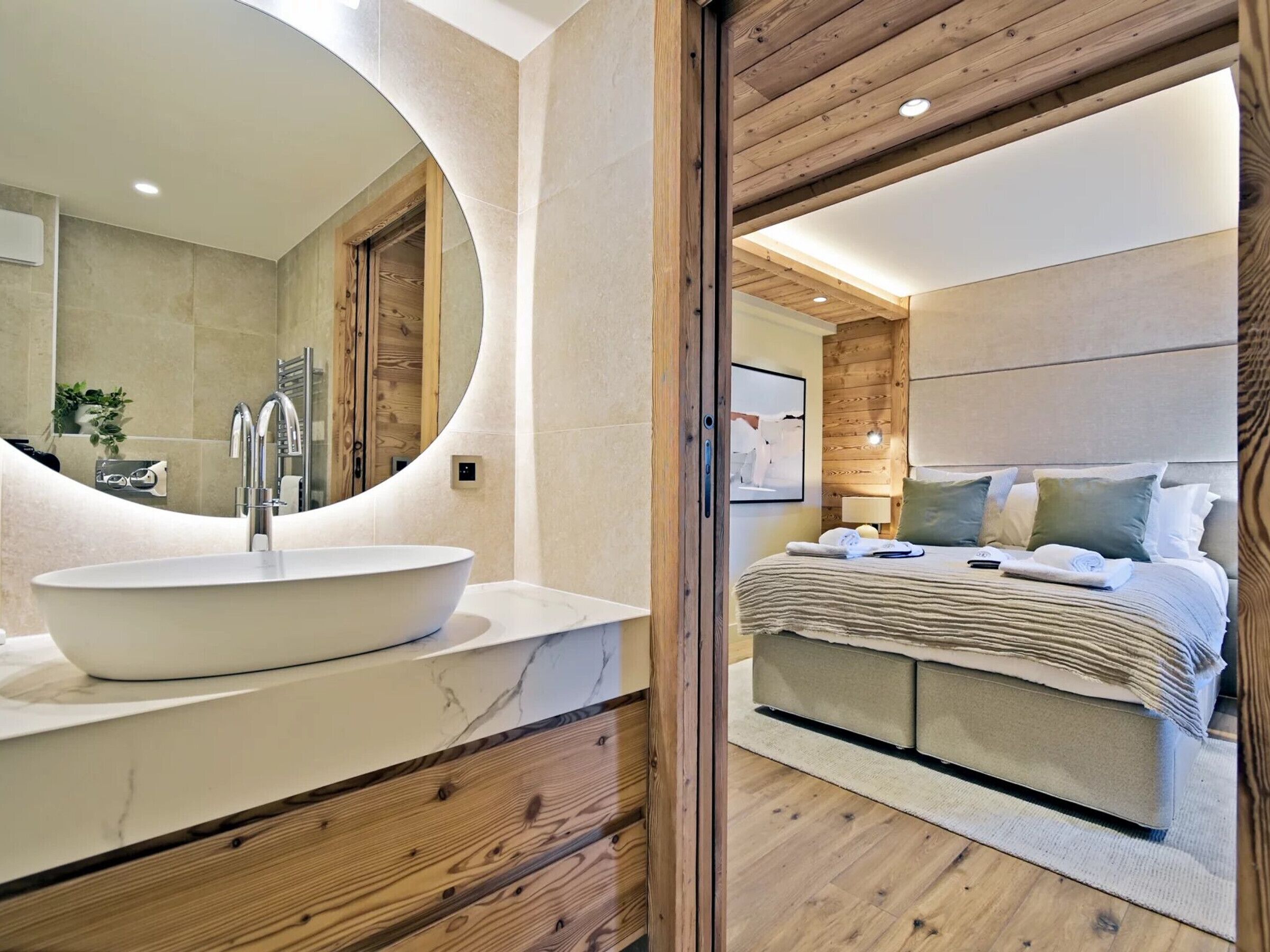 Une salle de bain moderne avec un grand lavabo ovale, un meuble-lavabo en bois et un mur miroitant.