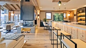 Une cuisine moderne dotée d’un îlot central, de poutres en bois et d’une grande fenêtre.