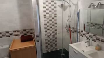 Chuveiro, toalhas de banho, sabonete, papel higiênico