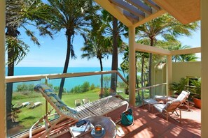 A balcony with a view of the ocean, palm trees, and lounge chairs. - Port Ridge; The Hill Penthouse (Port Douglas)
