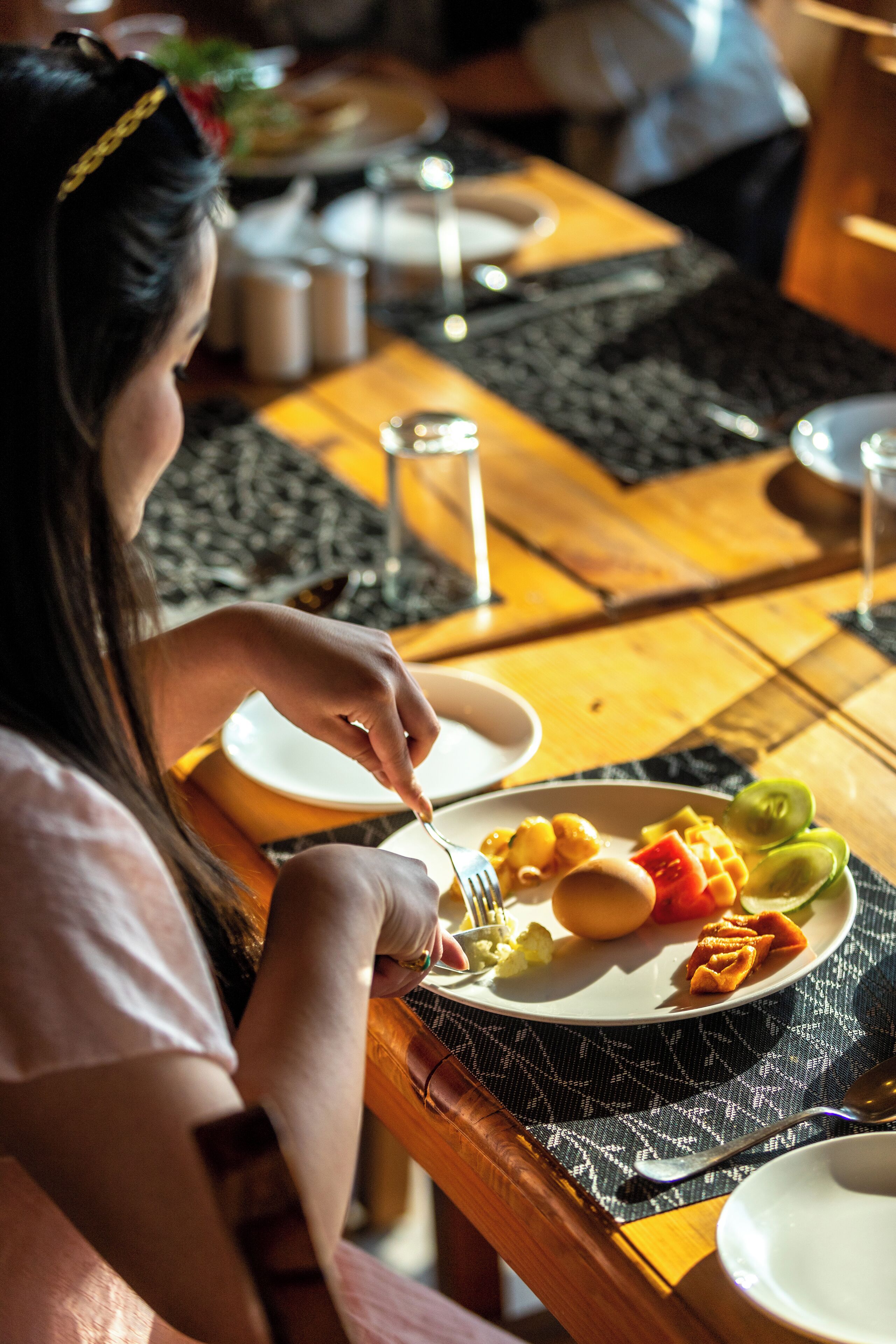 Una mesa de comedor con un plato de comida, un tenedor y un vaso de agua.