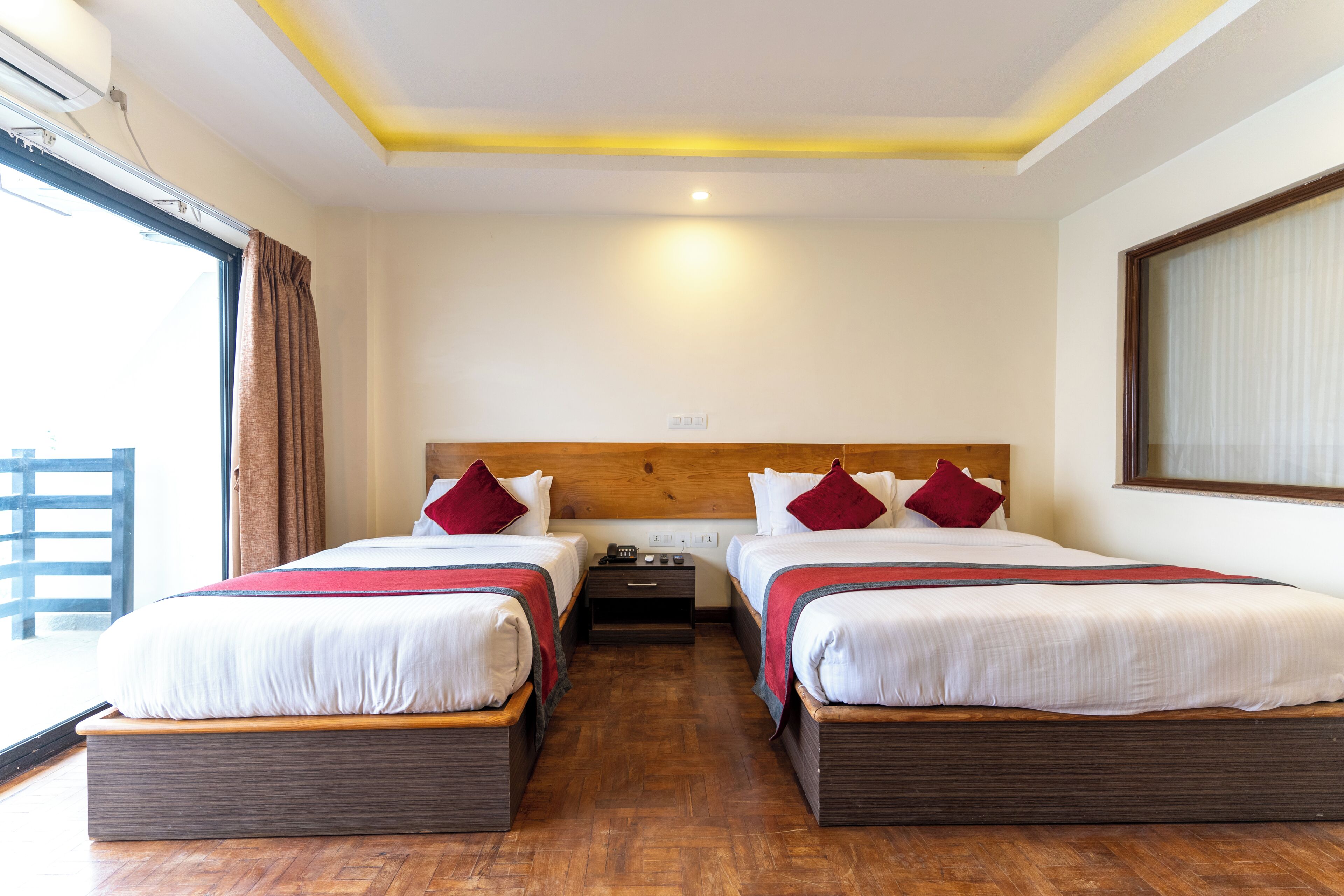 Habitación de hotel con dos camas, cabeceros de madera y un ventanal con cortinas.