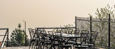 A terrace with outdoor seating, a potted plant, and a metal fence.