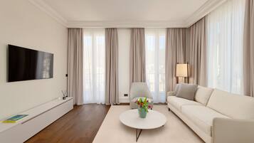 A modern living room with a flat-screen TV, a white sofa, a round coffee table, and a lamp.