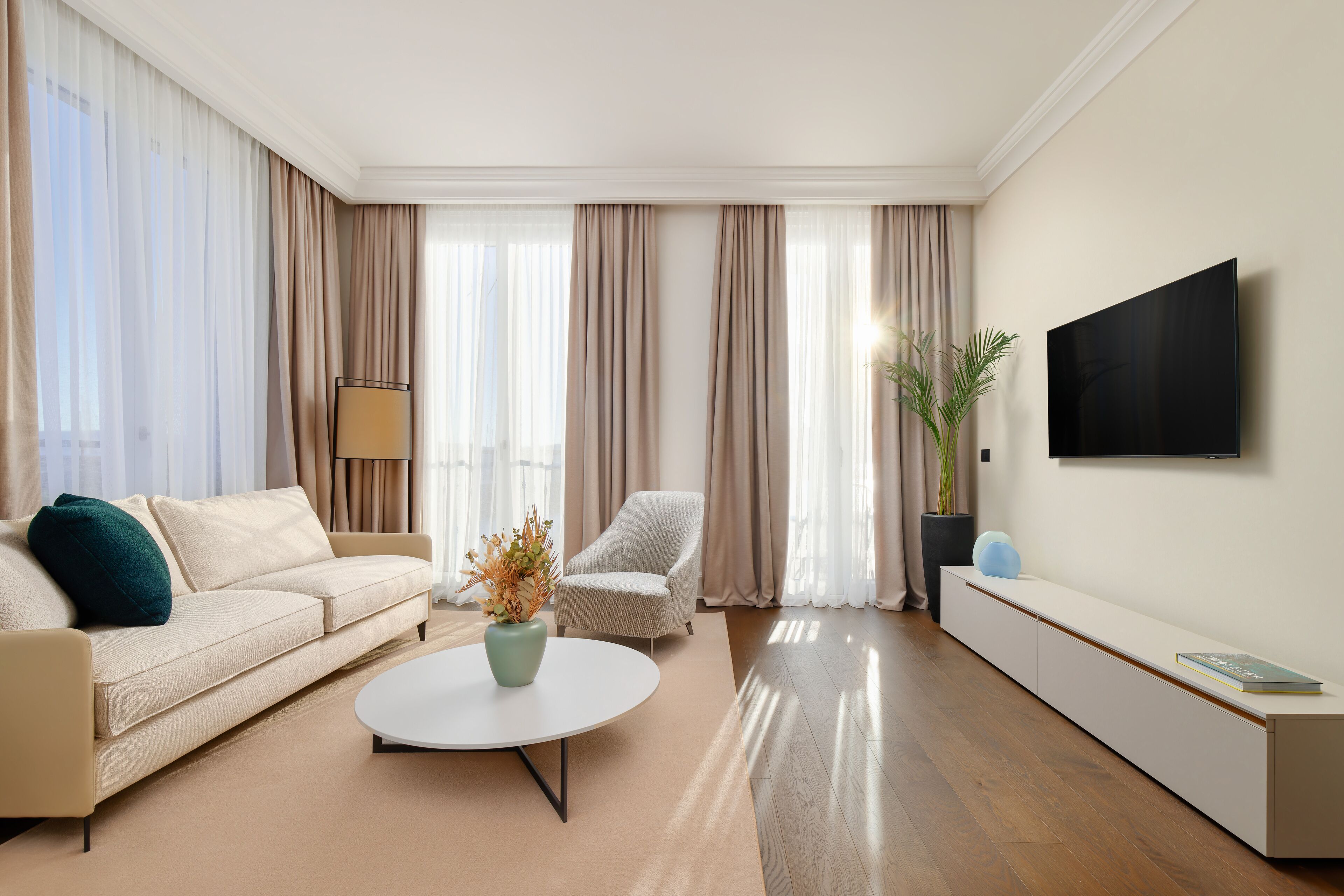 Uma sala de estar moderna com sofá, poltrona, mesa de centro e televisão de tela plana na parede.